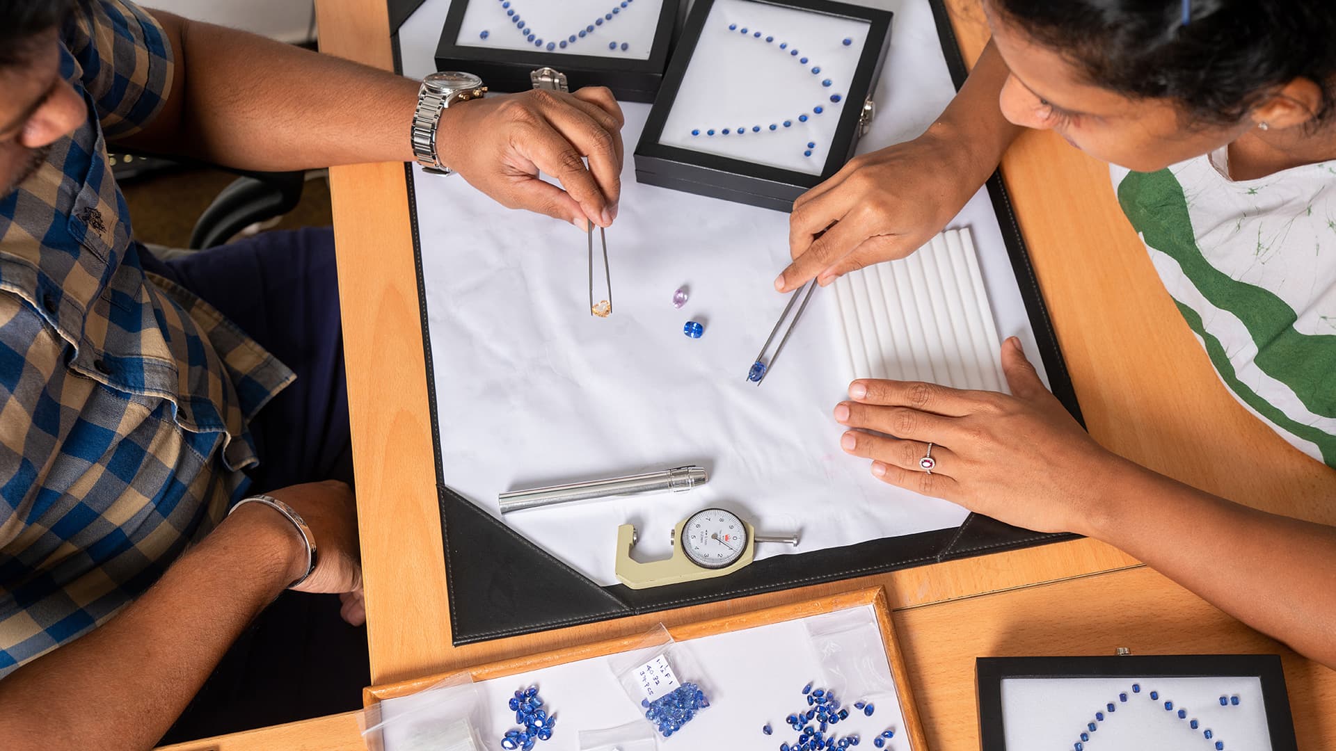 A Rohan specialist selecting loose Ceylon sapphires under a loupe