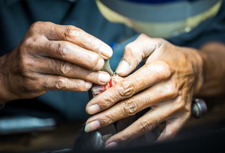 A master lapidary faceting a sapphire on a dop stick